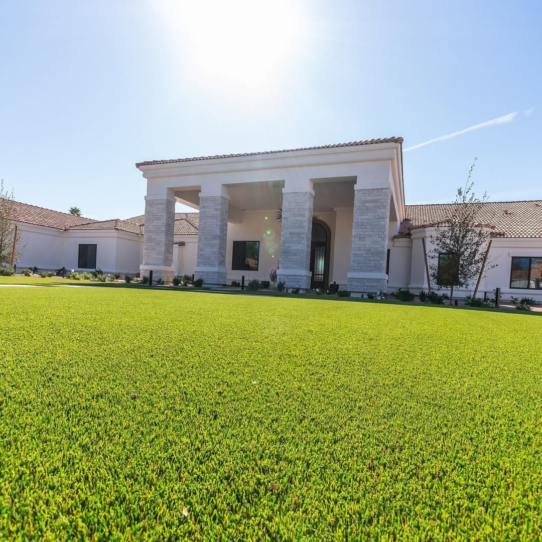 Large artificial grass lawn with a house in the background